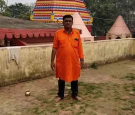 Astrologer Ramapada Acharjee in sacred orange attire at a traditional Hindu temple during a spiritual visit